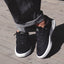 Pair of Shoreline Del Mar sneakers facing forward on wooden deck, highlighting black sustainable design and cushioned comfort.
