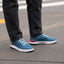 Shoreline Del Mar facing right on feet, men's blue sneaker with cushioned sole, elastic laces, and red-white accents for comfort.