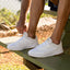 Shoreline Del Mar white sneakers facing right with man tying laces, showcasing lightweight, cushioned comfort and arch support