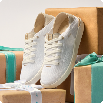 White lace up sneakers with toes facing the viewer, displayed on wrapped beach themed gifts