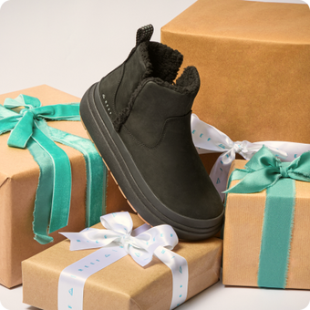 Black high top shoe facing lower right, displayed on wrapped gift boxes with turquoise and white ribbons