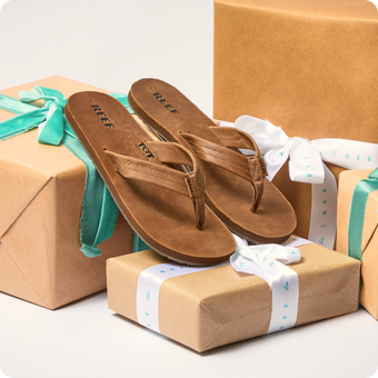 Brown flip flops facing lower right, arranged on wrapped gift boxes with teal ribbons