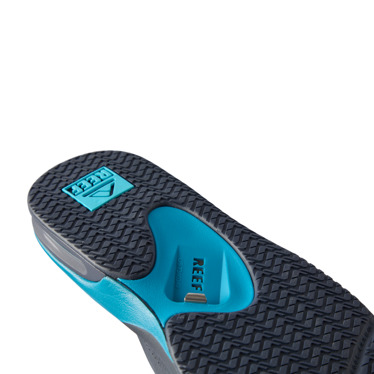 REEF Fanning flip flop outsole facing viewer, toe pointing upper left, close-up of textured tread and arch support
