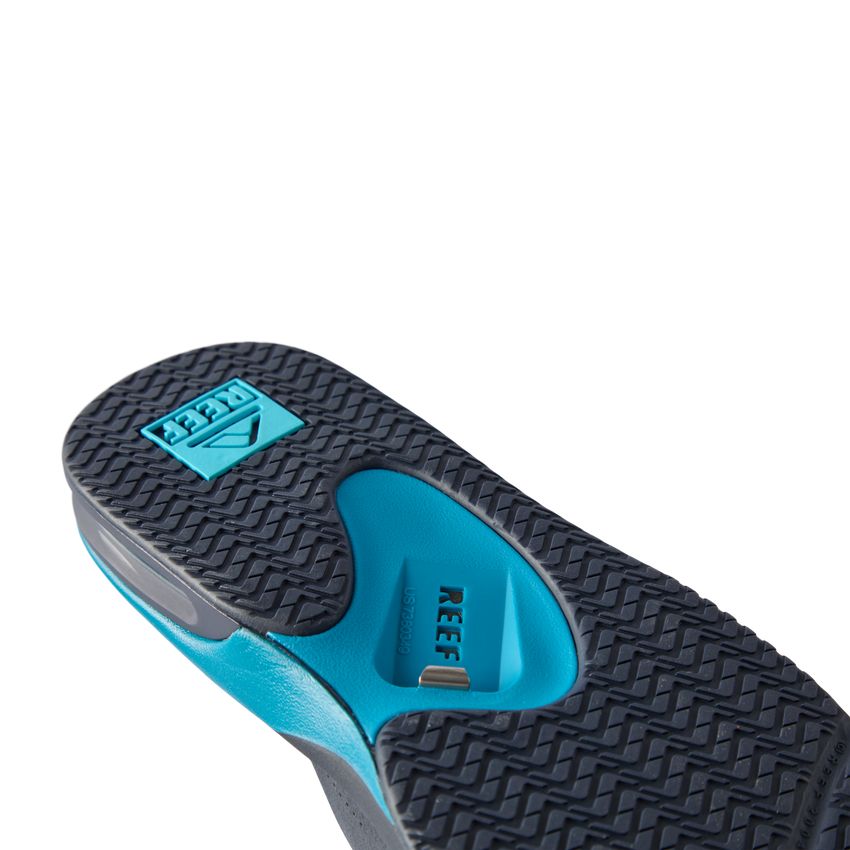 REEF Fanning flip flop outsole facing viewer, toe pointing upper left, close-up of textured tread and arch support