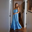 Woman wearing a light blue Lainey Maxi Dress standing in a hallway, showcasing its flowing beach-inspired design.