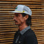 Side profile of man wearing Blackball Hat with mesh back, surf-inspired design, and lightweight comfort features