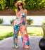 Woman wearing Eve Wide Leg Romper with vibrant floral print, standing outdoors in bright sunlight, facing forward.