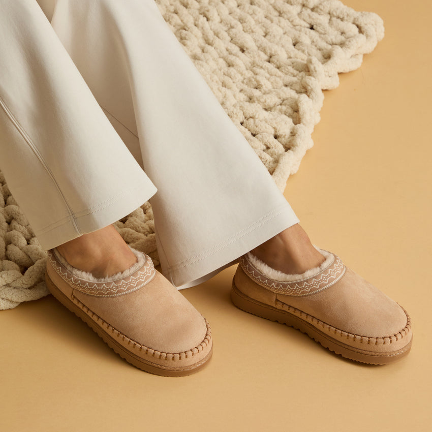 Indie Slipper women's beige slippers facing forward, with patterned trim and cushioned footbeds