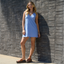 Woman wearing Vista Luxe Siaa sandals facing forward, standing against a brick wall in a light blue dress.