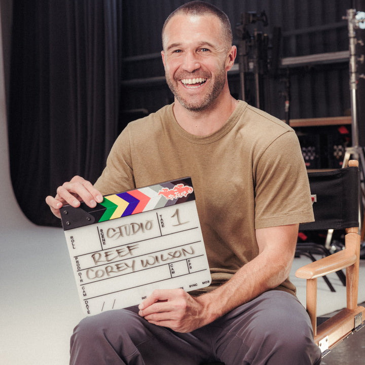 Smiling man holding a film clapperboard in a studio setting