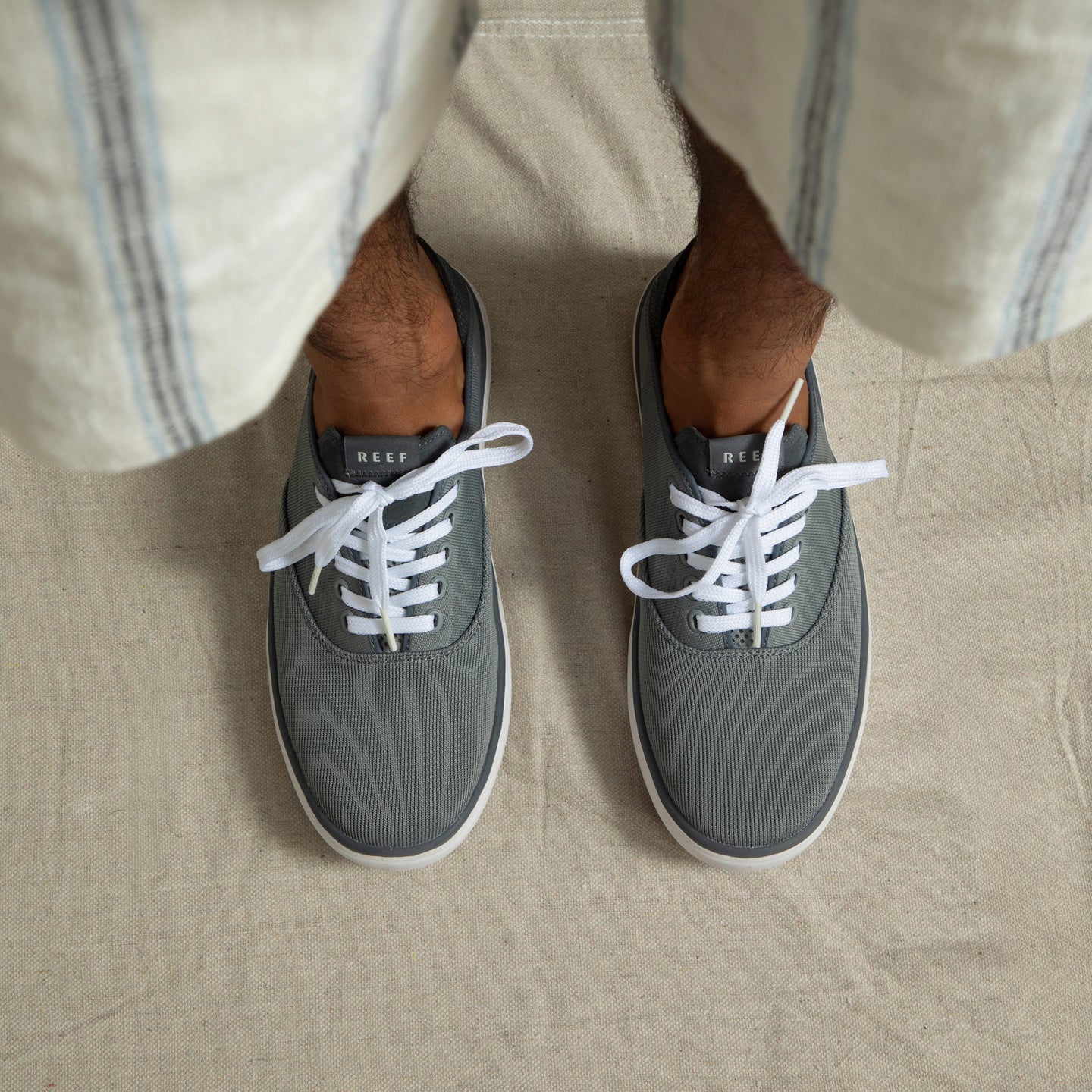 Top-down view of feet wearing grey Neptune Lido sneakers facing forward with white laces, showcasing lightweight, cushioned comfort.