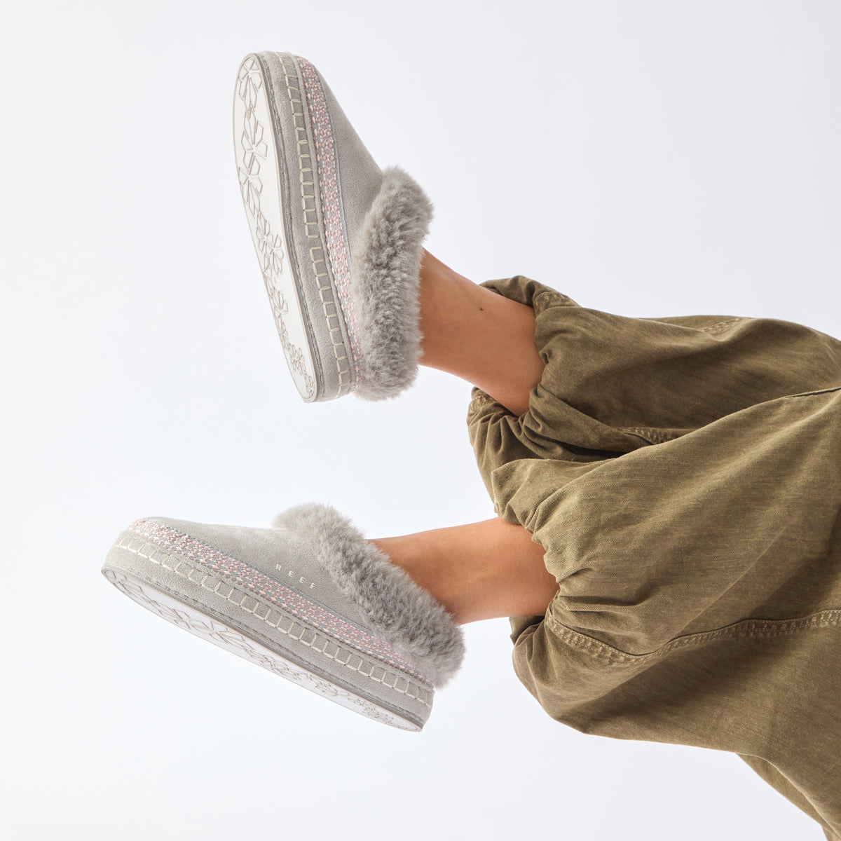 Mikayla grey plush faux fur lined footwear with soles facing left and toward the viewer