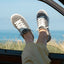 Pair of Neptune Alana sneakers facing forward, worn by a woman relaxing with feet out the car window by the beach.