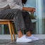 Side view of white Neptune HT sneaker on person seated, featuring lightweight, cushioned, water-friendly design with arch support.