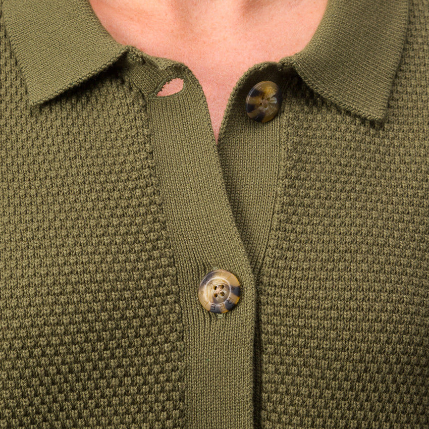 Close-up of the button and textured fabric front of the olive green Up North Sweater Top for women.