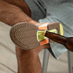 Fanning + sandal sole facing up with built-in bottle opener removing a bottle cap, showcasing water-friendly durable design