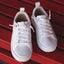 Top-front view of white Lay Day Lite women's sneakers with lightweight breathable mesh and cushioned arch support on red bench.