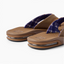 Fanning men's flip flops facing left, close-up of cushioned footbeds and plaid straps