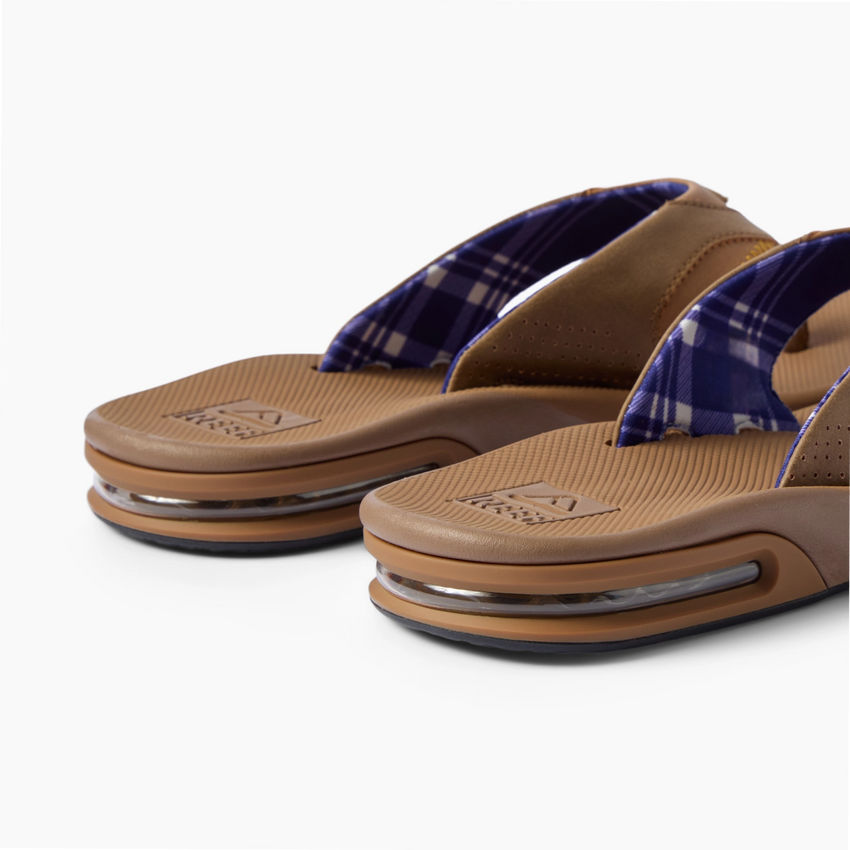 Fanning men's flip flops facing left, close-up of cushioned footbeds and plaid straps
