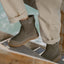 Close-up of brown ankle boots, one facing left and one facing right, worn on a wooden boardwalk over water