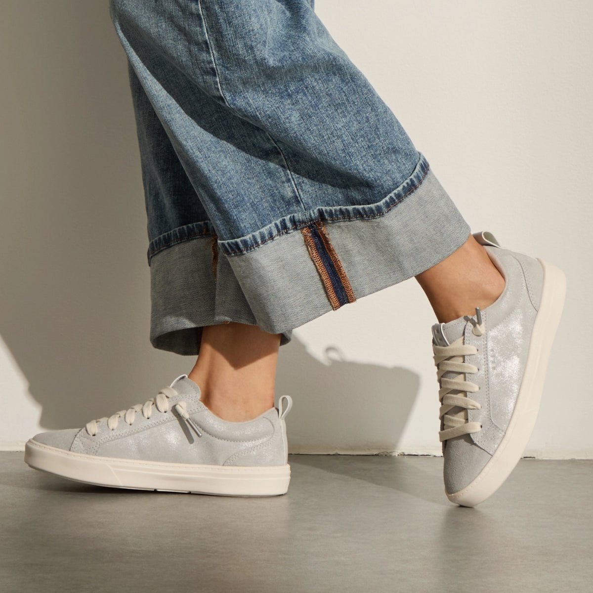 Lay Day Lite silver sneakers, one facing left and one right, styled with wide leg jeans for comfortable everyday wear