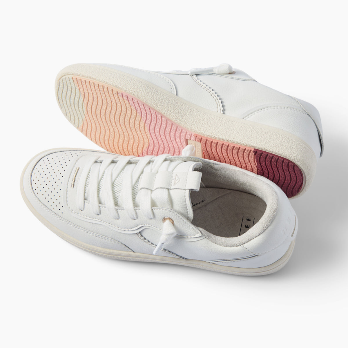 Kickback white sneakers facing left, with lace up uppers and textured pink outsoles for beach inspired comfort