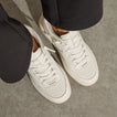 Kickback white sneakers facing lower right, top down close up of perforated toe boxes, laces, and cushioned soles