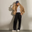 Kickback white sneakers facing forward on a model wearing black pants and a tan jacket