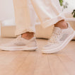 White sneakers worn indoors, with one shoe facing left and the other facing right, shown from the side