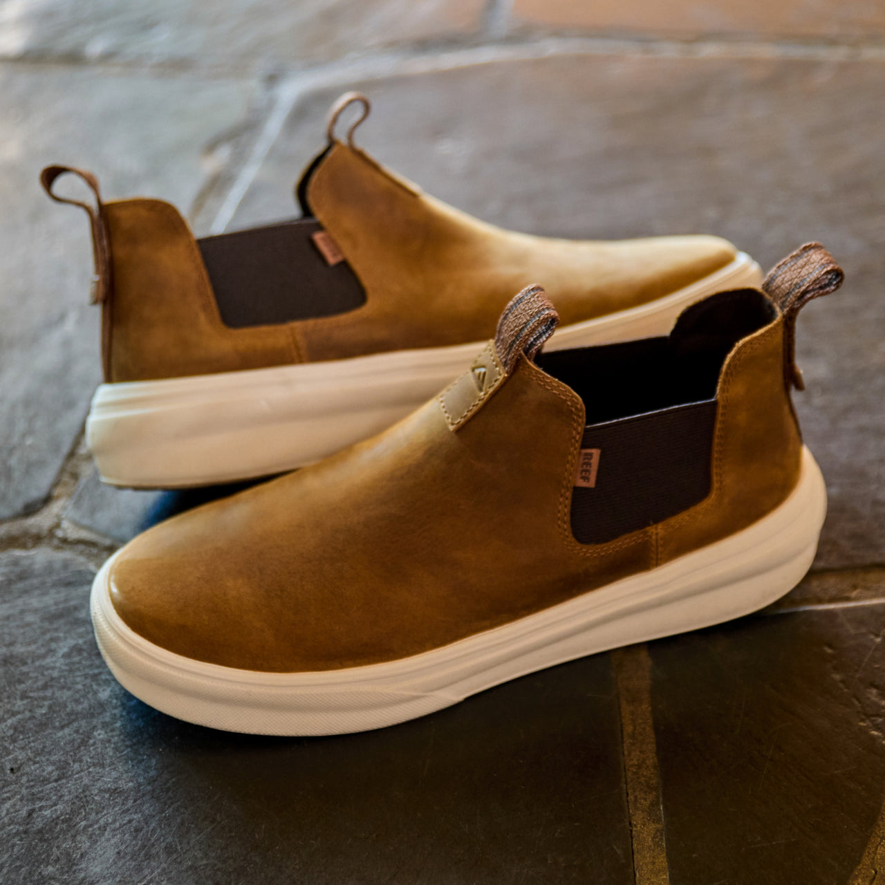 Pair of brown Evo mid-cut shoes facing right on stone floor, showing smooth leather upper and white cushioned sole