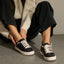 Lay Day Lite black sneakers facing toward the viewer on a model with cushioned soles for everyday comfort