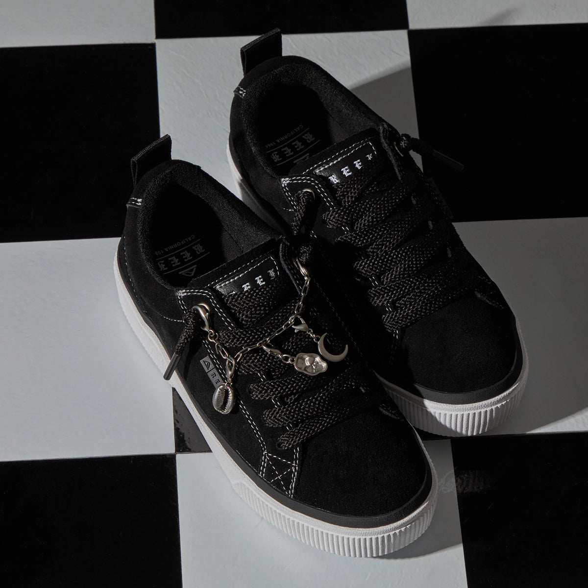 Lay Day Dawn black sneakers facing toward the lower right on a checkerboard surface