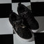Lay Day Dawn black sneakers facing toward the lower right on a checkerboard surface