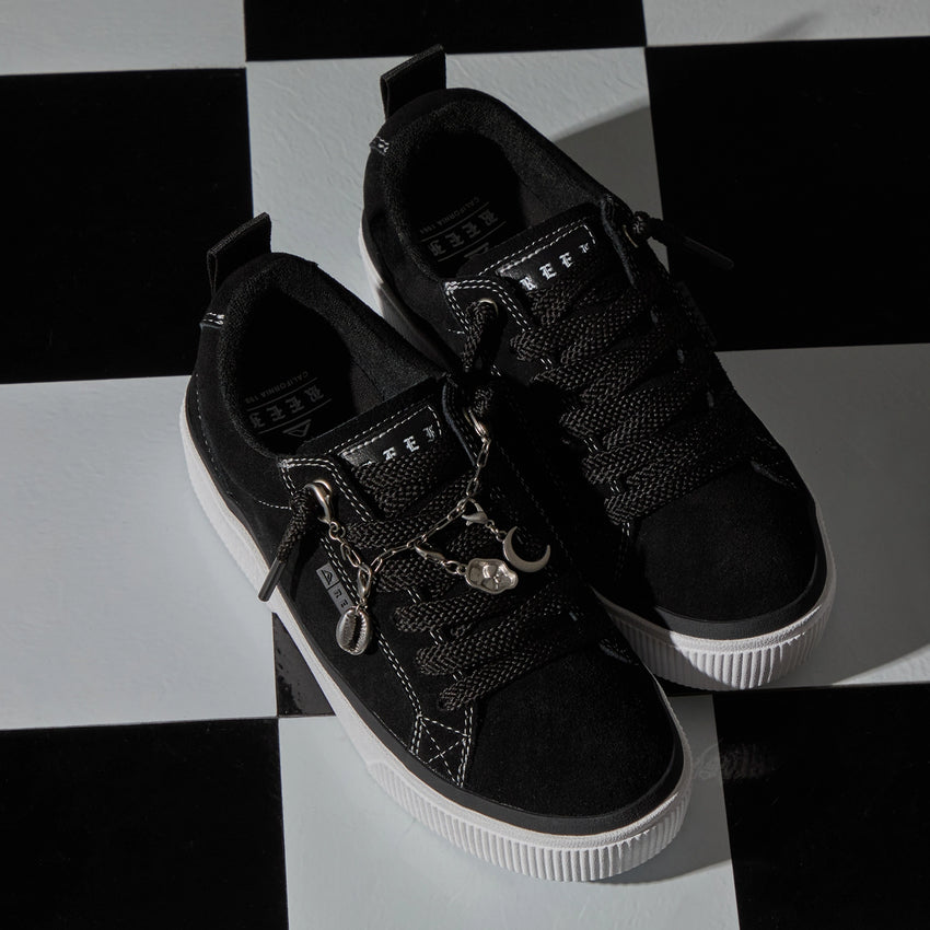 Lay Day Dawn black sneakers facing toward the lower right on a checkerboard surface