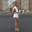 Side view of a woman wearing Vista Luxe Liah sandals with platform soles, holding white flowers and a coffee cup.