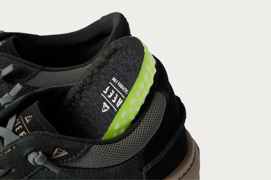 Close-up of the heel and collar of a black REEF sneaker showing padded interior and anatomical arch support details.
