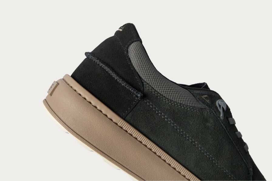 Close-up of left black sneaker facing right, showing heel and midsole with soft-rebound cushioning and arch support design.