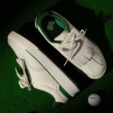 Top and side view of white and green Onshore Pebble men's shoes on green turf with a REEF golf ball nearby