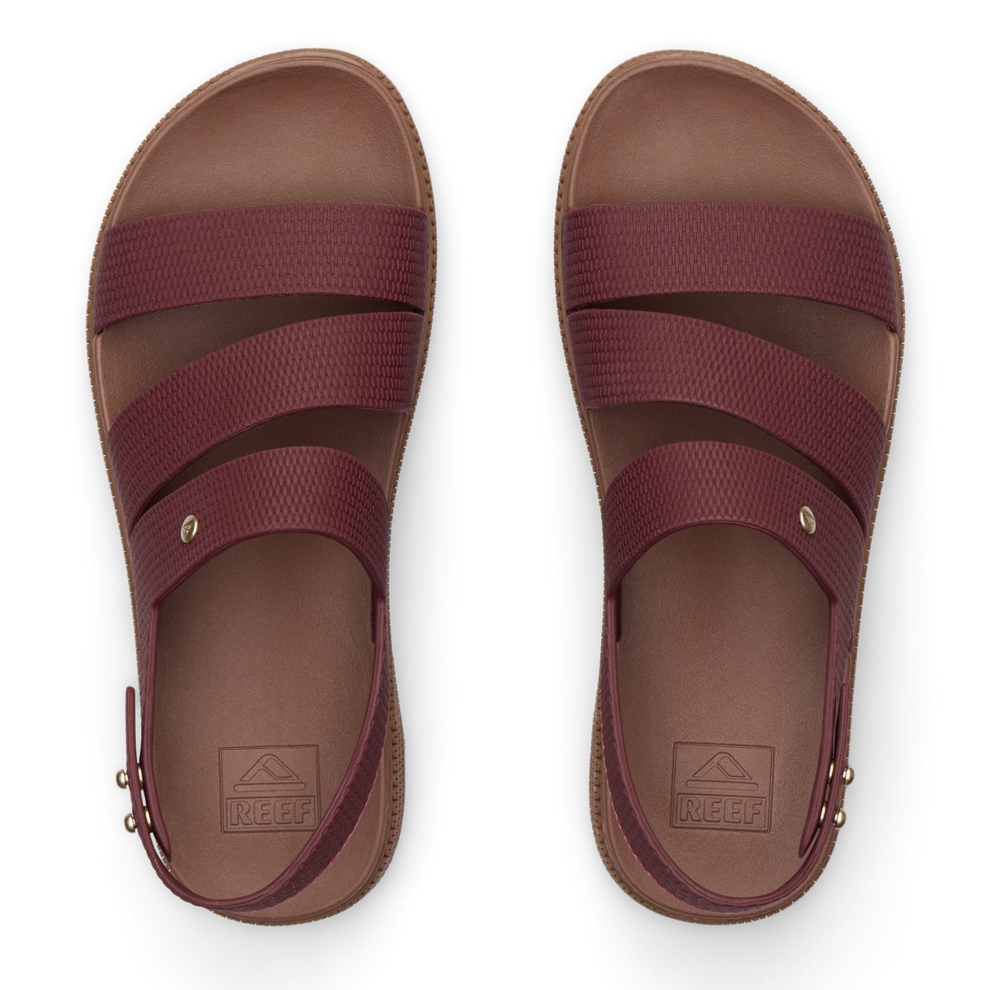 Top view of maroon REEF sandals with three straps and molded footbeds, designed for beach comfort and durability.
