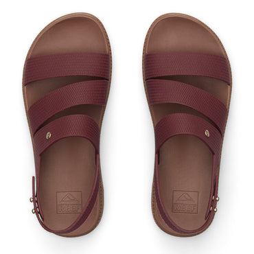 Top view of maroon REEF sandals with three straps and molded footbeds, designed for beach comfort and durability.