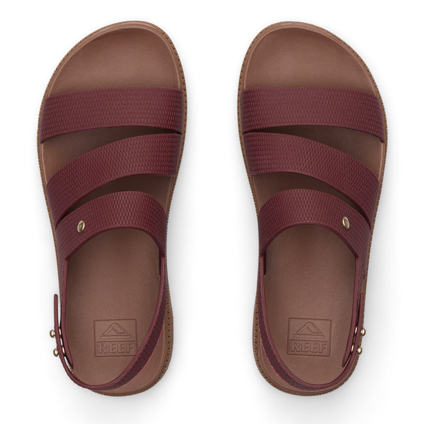 Top view of maroon REEF sandals with three straps and molded footbeds, designed for beach comfort and durability.