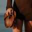 Vista Vay-Cay brown flip flop sandals held by a woman, showing top view of the footbed with surf-inspired comfort design.