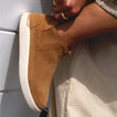 Side view of Neptune Athena slip-on shoe in tan suede with cushioned sole on model’s foot, highlighting arch support and casual style.