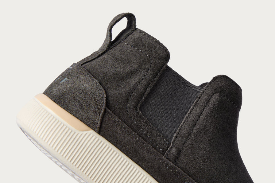 Close-up of the back heel and side of a right black suede slip-on sneaker featuring soft cushioning and arch support.