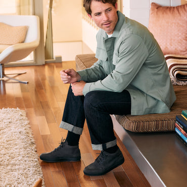 Laguna Spiniker black leather boots facing left worn by a seated man