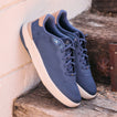 Pair of navy blue lace-up sneakers facing toward the lower right on a weathered wooden step