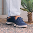 Navy REEF sneakers facing toward the right foreground on a person outdoors