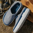 Close-up of gray and blue slip-on shoes, toes facing lower left and upper right, showing cushioned footbeds and side profile.