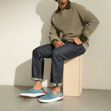 Del Mar Slip On blue slip on sneakers facing left on a seated man with cushioned soles