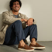 Laguna Slip On brown slip on shoes facing toward the viewer on a seated man